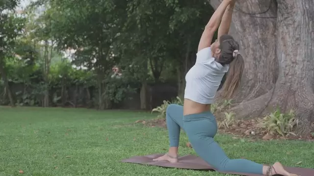 女孩在草坪上做瑜伽姿势视频素材插图
