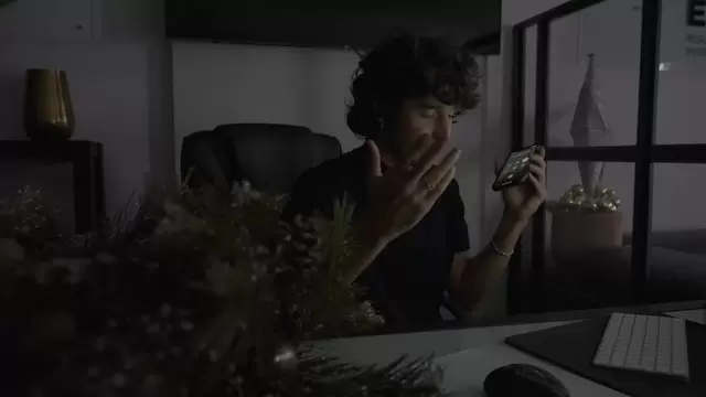 一个男人坐在办公桌前，用手机聊天视频素材插图