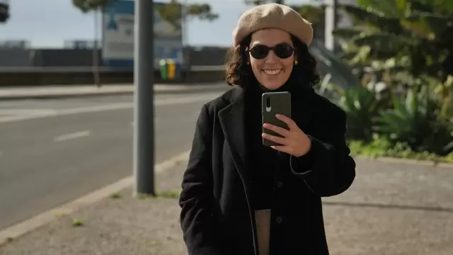 女人在街上用智能手机拍摄视频素材插图