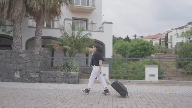 一个女人带着手提箱走到酒店视频素材插图