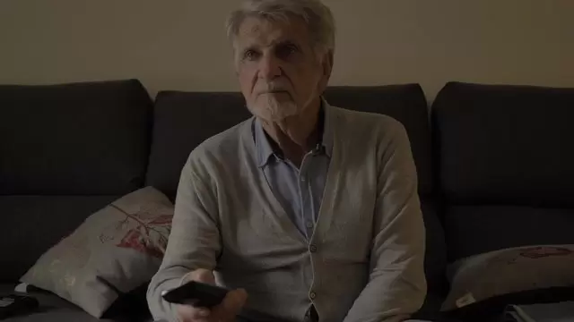 一个老人坐在沙发上看电视视频素材插图