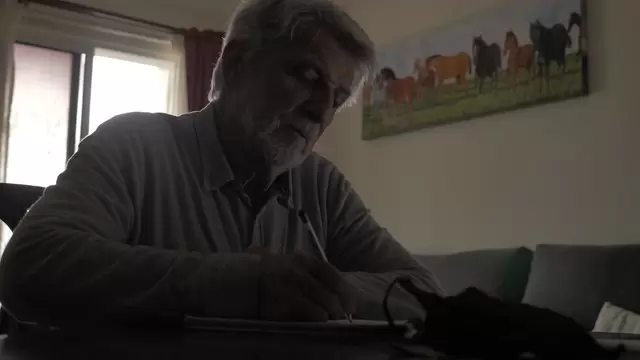 老人在笔记本上写字视频素材插图